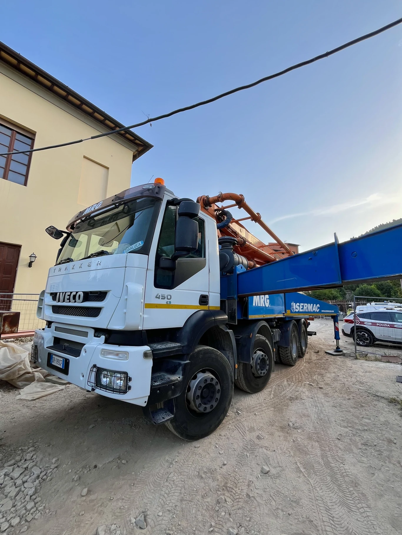 Autopompa a braccio MRG con pompa Sermac ripiegata, in sosta in una via stretta a fianco del cantiere