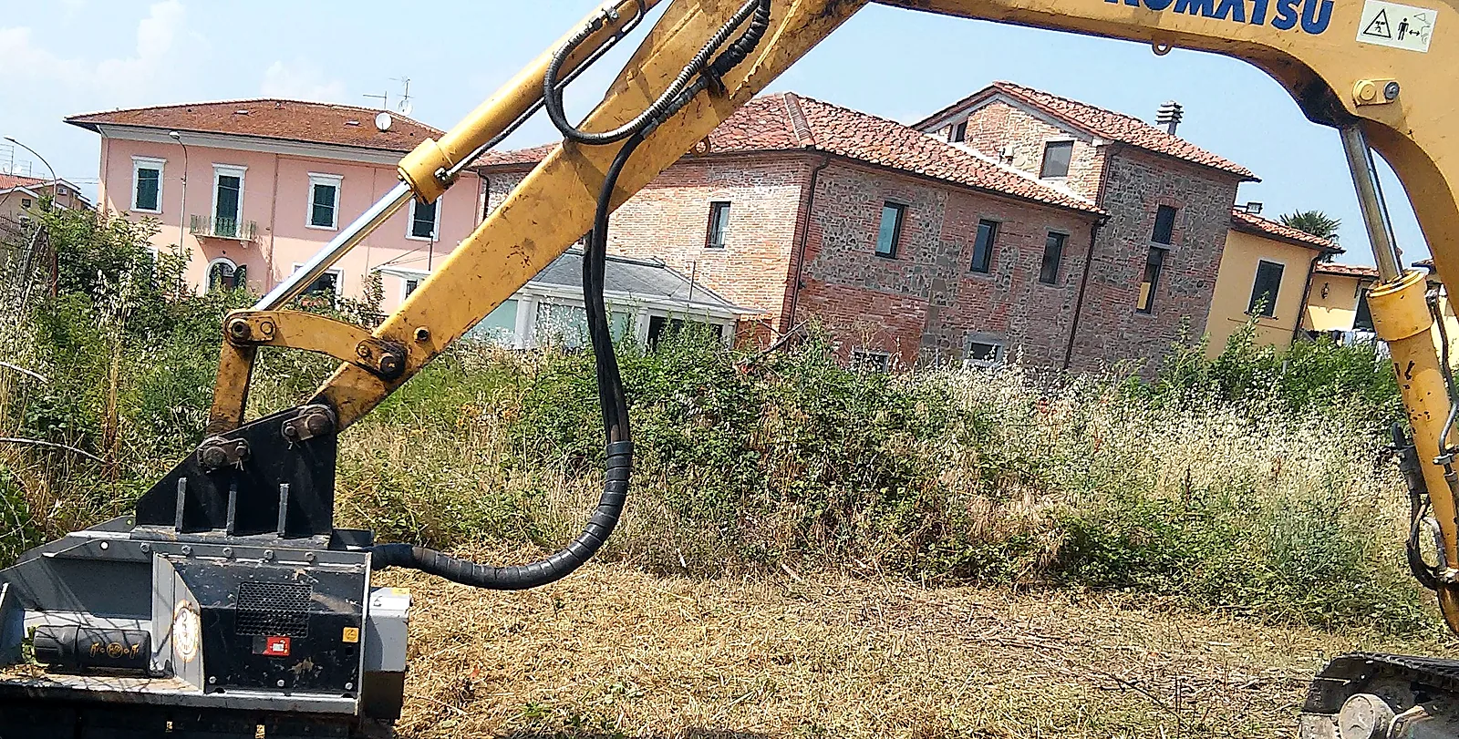 Escavatore Komatsu MRG al lavoro accanto alle case