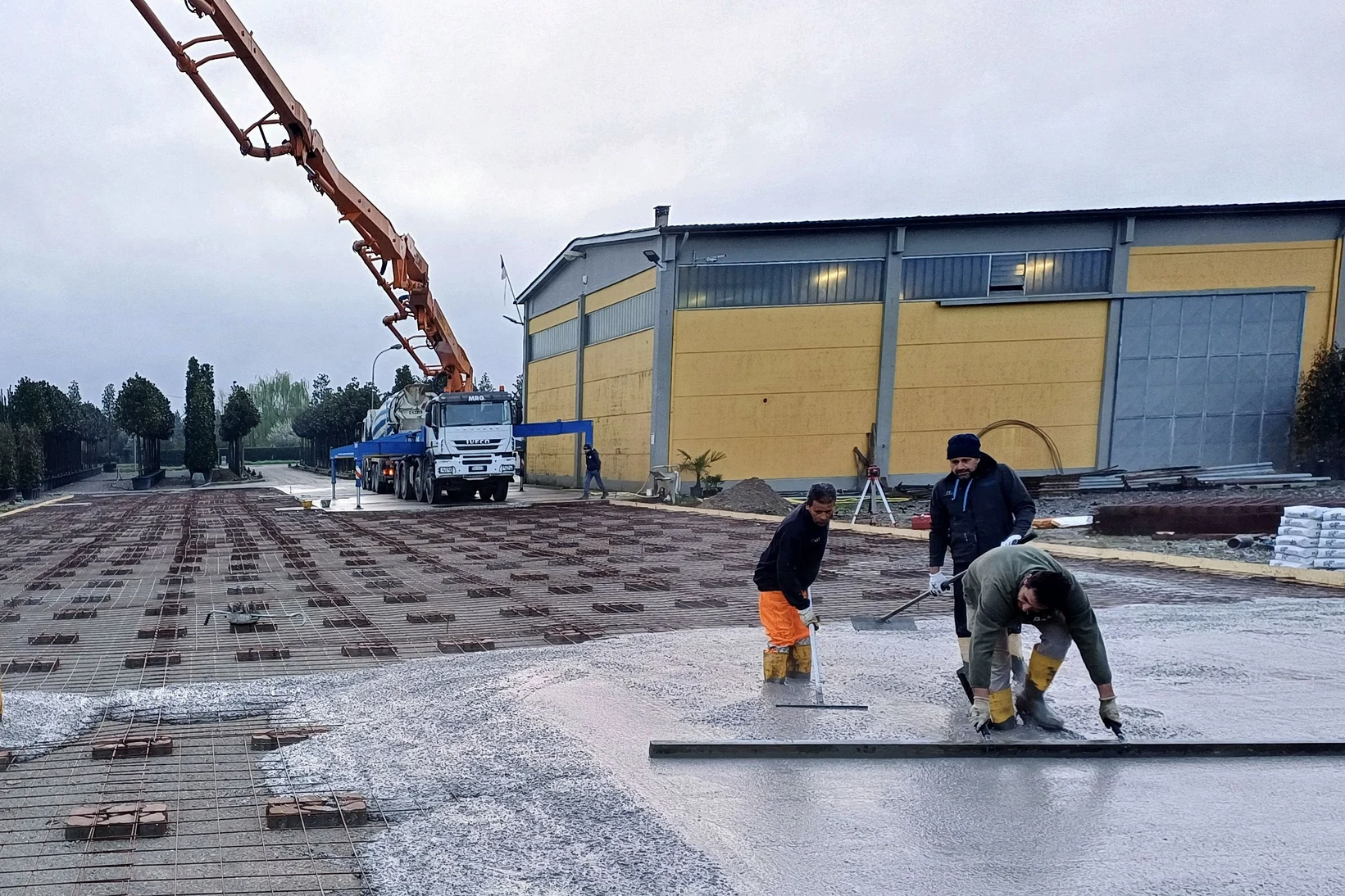 Squadra MRG durante il getto di una pavimentazione industriale, con autopompa a braccio in azione